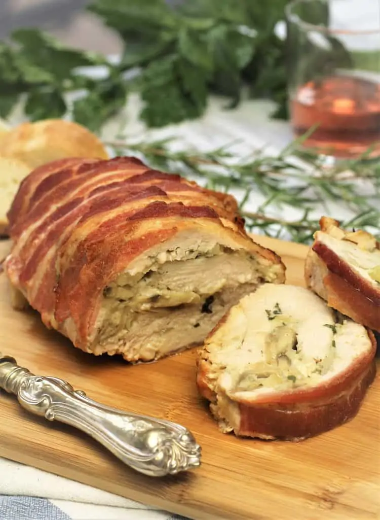 bacon covered turkey roulade sliced on wood board 