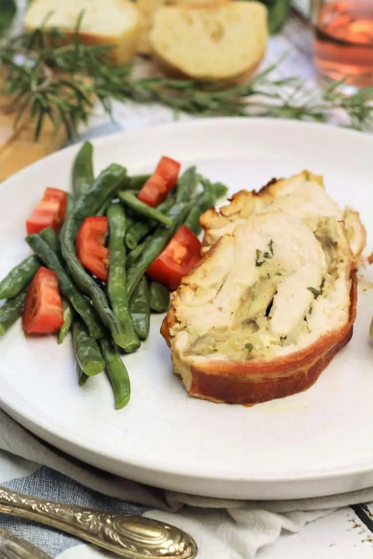 slice of stuffed turkey roulade on plate with green bean salad