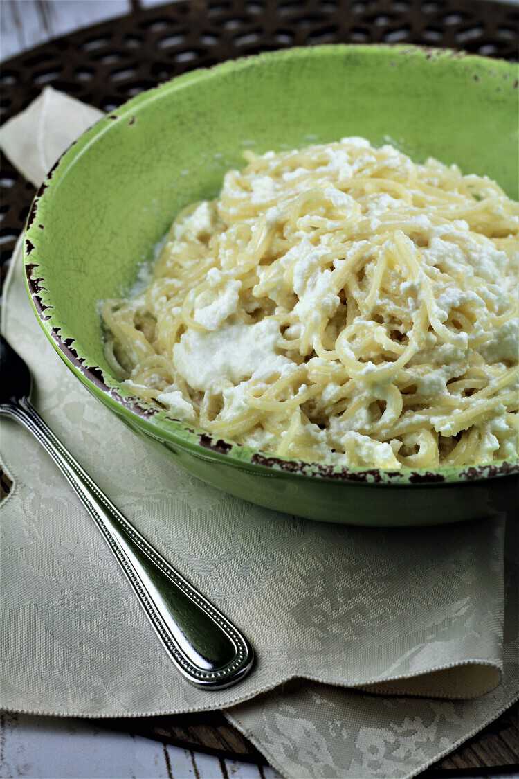 pasta with ricotta in a green bowl and fork on side