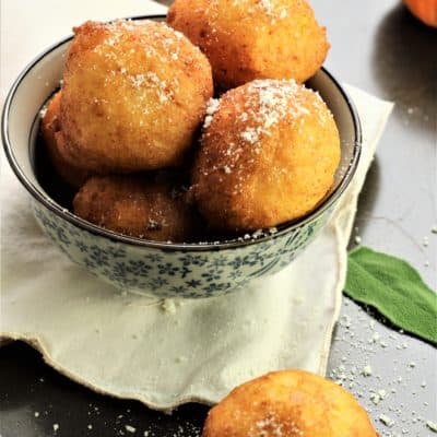 bowl of savory pupmpkin ricotta fritters with mini pumpkins in background