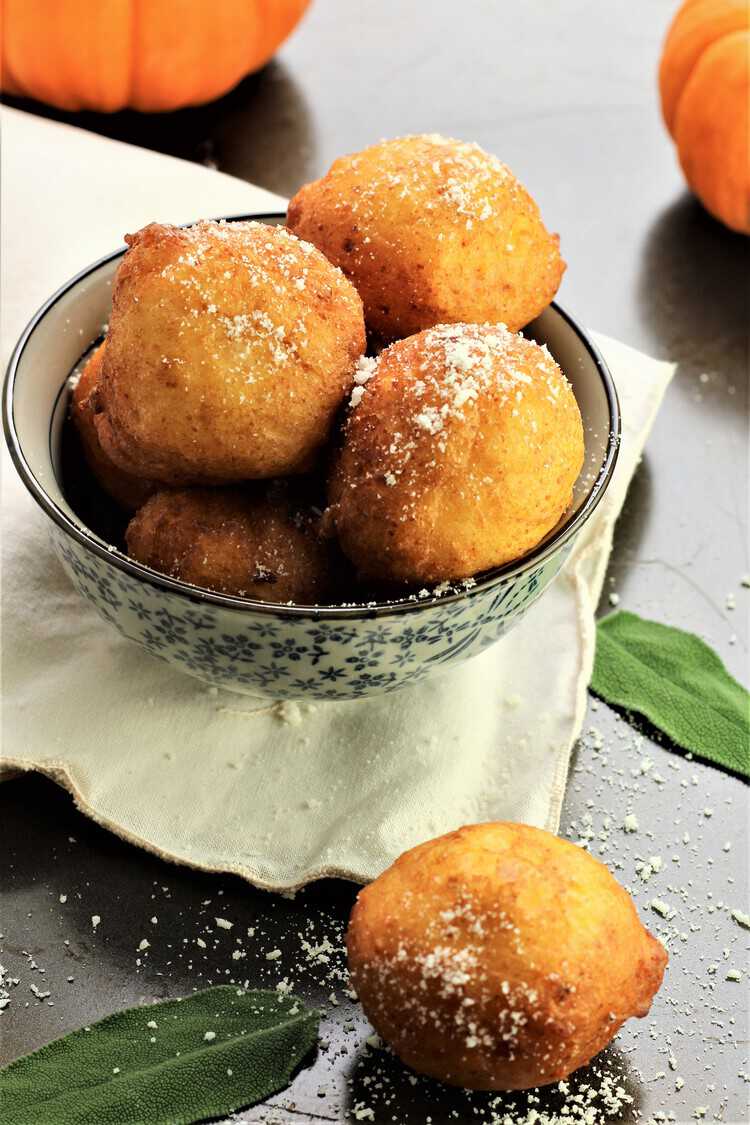 bowl of savory pupmpkin ricotta fritters with mini pumpkins in background