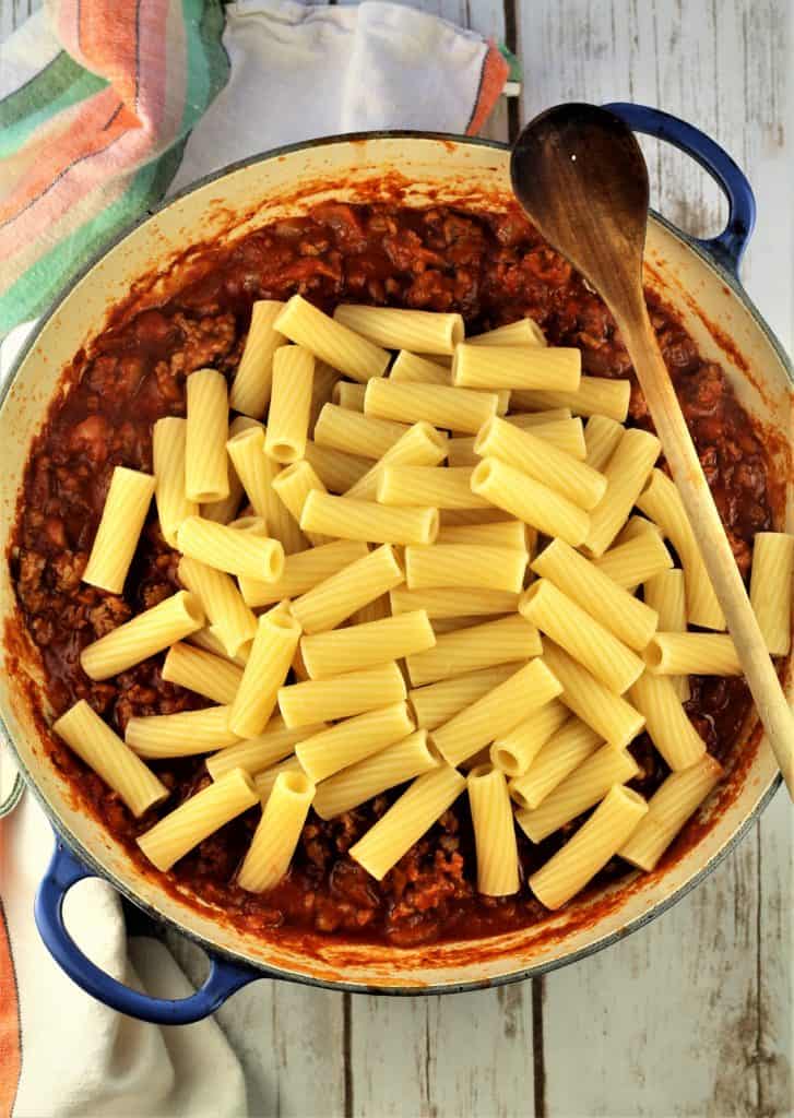 rigatoni pasta over sausage tomato sauce in skillet 