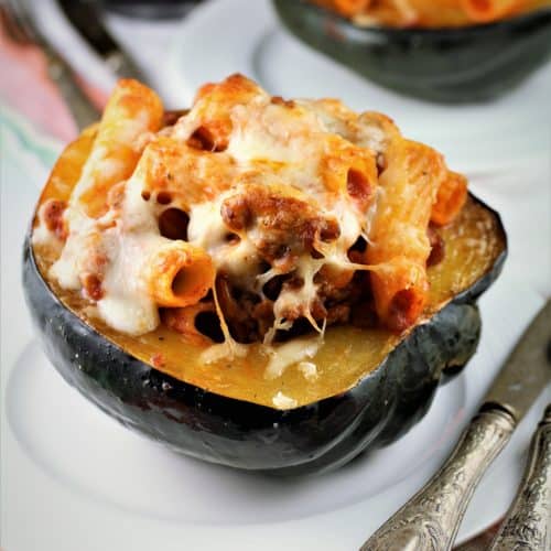 Sausage and Pasta Stuffed Acorn Squash on a plate with utensils on side