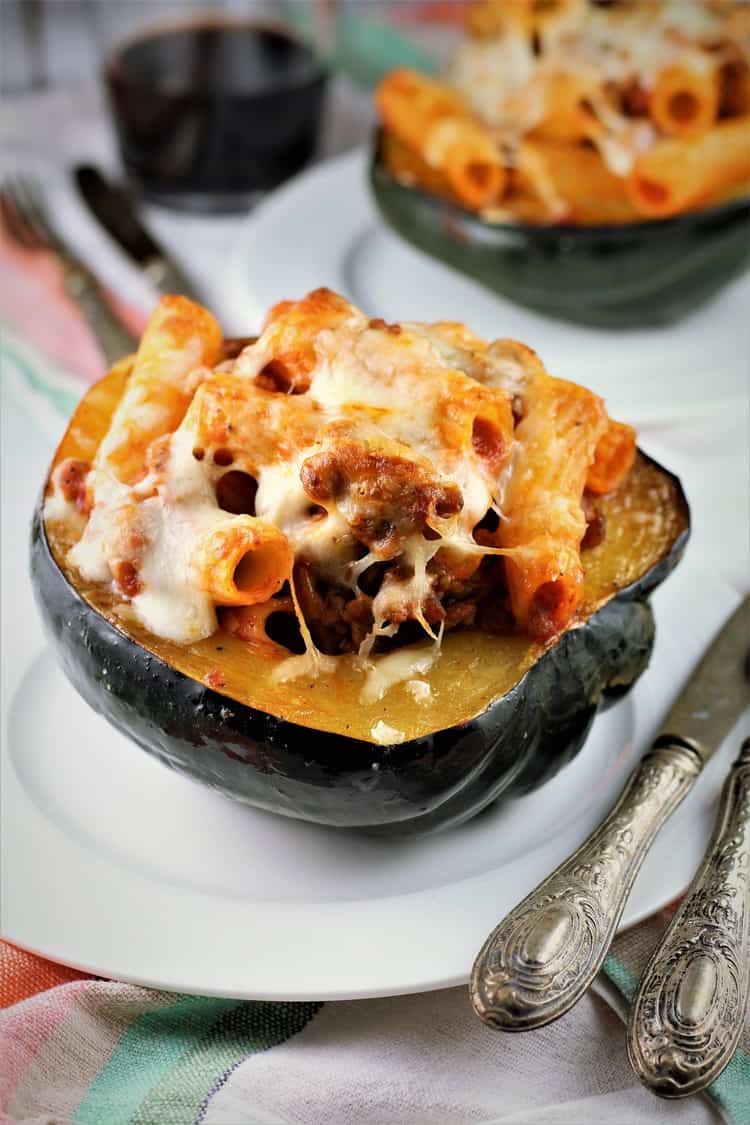 Sausage and Pasta Stuffed Acorn Squash on a plate with utensils on side