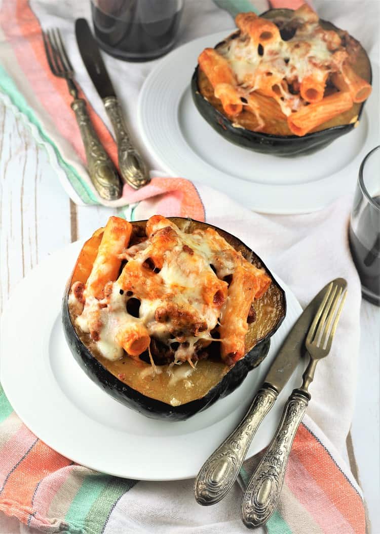 two acorn squash halves filled with pasta topped with mozzarella