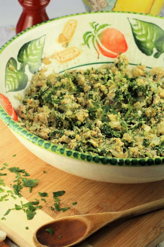 bowl with spinach and mushroom filling on a wooden board with wooden spoon in foreground