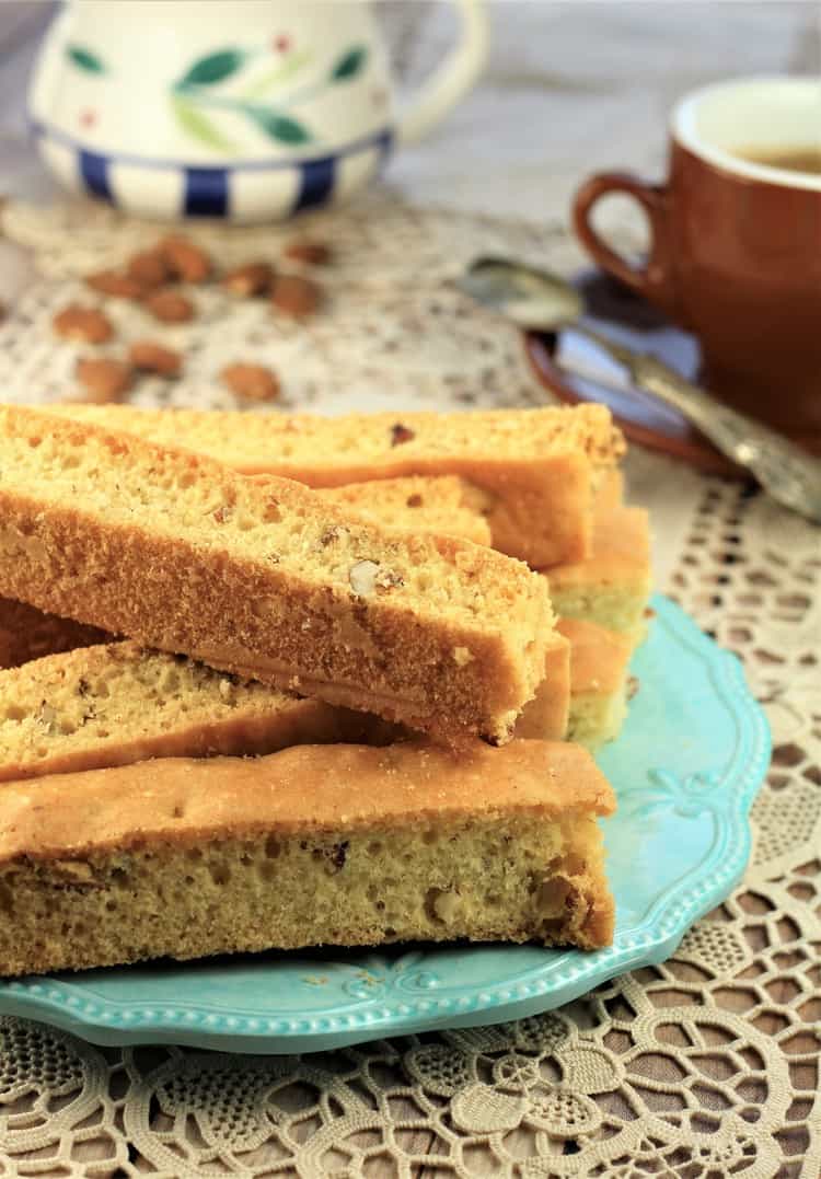 almond biscotti on blue plate with coffee cup and milk bowl behind it