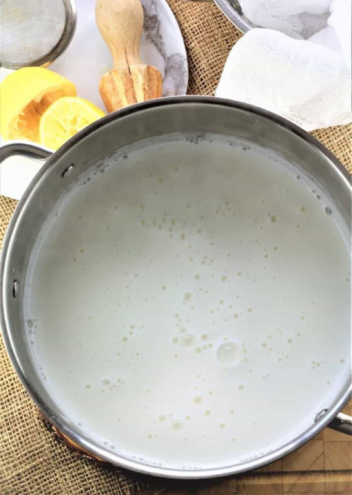 Milk in large sauce pan simmering to make homemade ricotta.