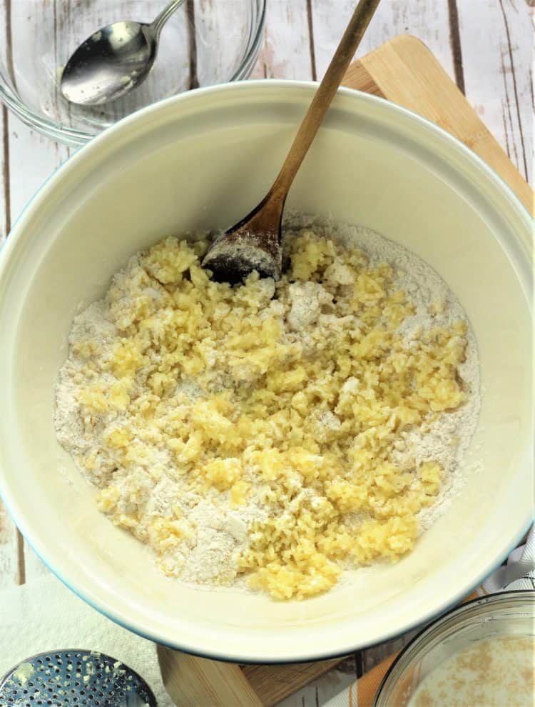 mixing bowl with flour and riced potatoes with wooden spoon in it