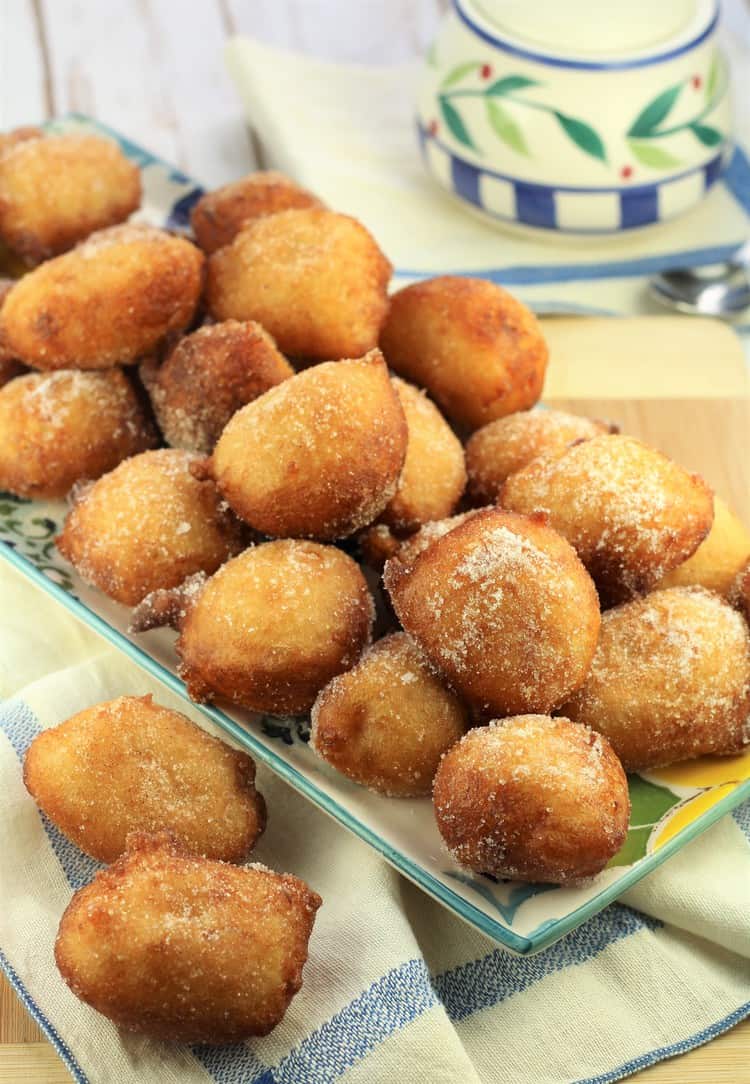 rectangular plate piled with potato sfinci and sugar bowl in background