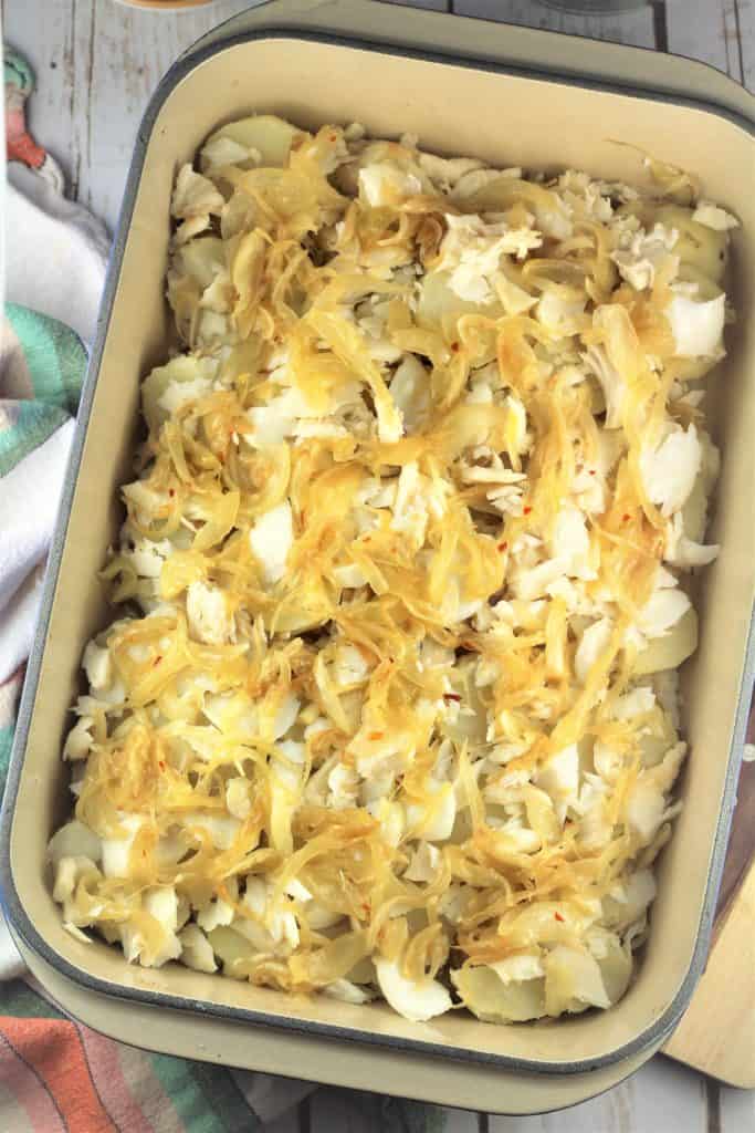 rectangular casserole dish with cod pieces and sauted onions