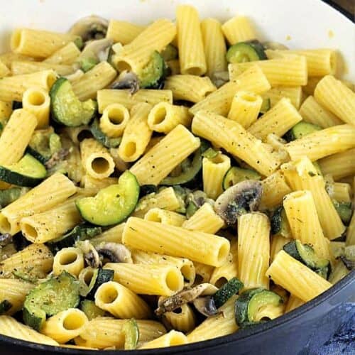 Pasta with zucchini and mushrooms in skillet.