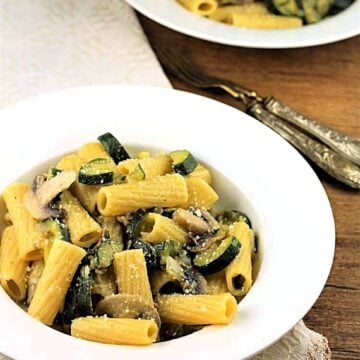 Zucchini mushroom pasta in bowl next to second bowl of pasta.