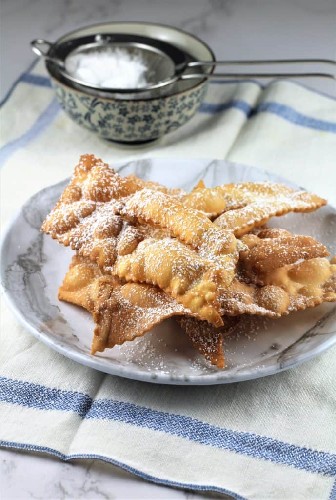 plate piled with fried dough strips dusted in powdered sugar