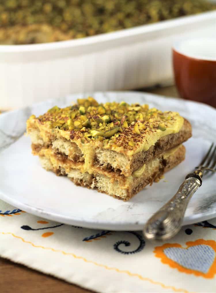 slice of pistachio tiramisu on white plate with fork 