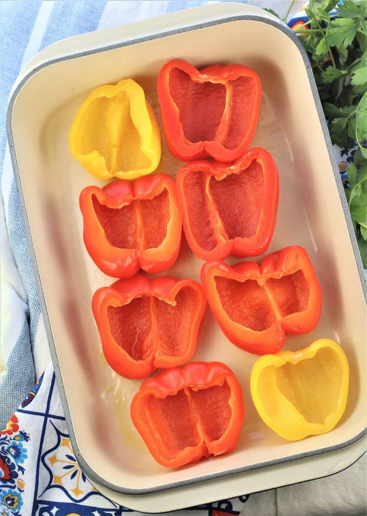 halved peppers on a baking pan with parsley on side