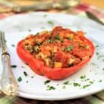 stuffed red pepper half on white plate sprinkled with parsley