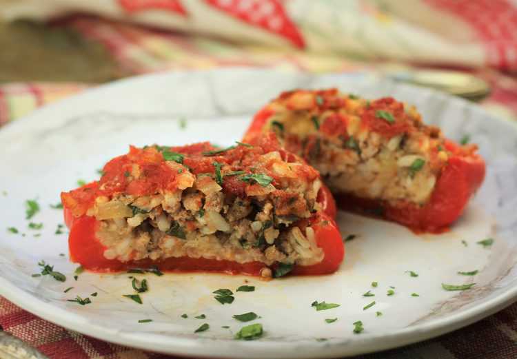 stuffed red pepper cut in half to show filling on white plate