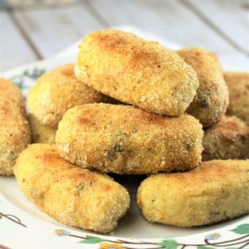 flowery plate piled with potato croquettes on wood board