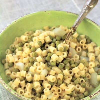 green bowl with pasta and peas and spoon