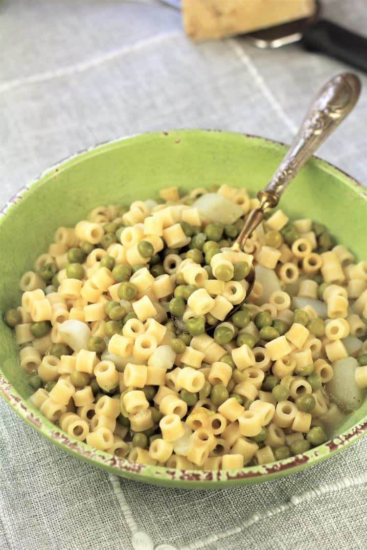 green bowl with pasta and peas with spoon in it