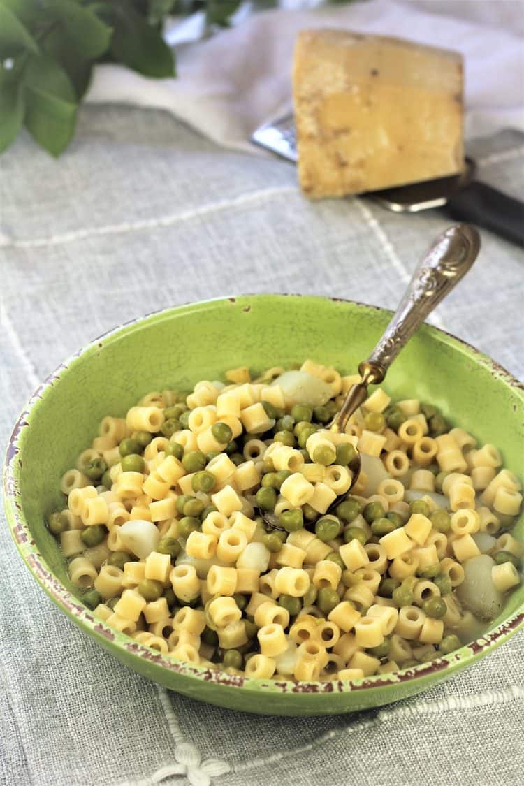 green bowl with pasta and peas with spoon in it 