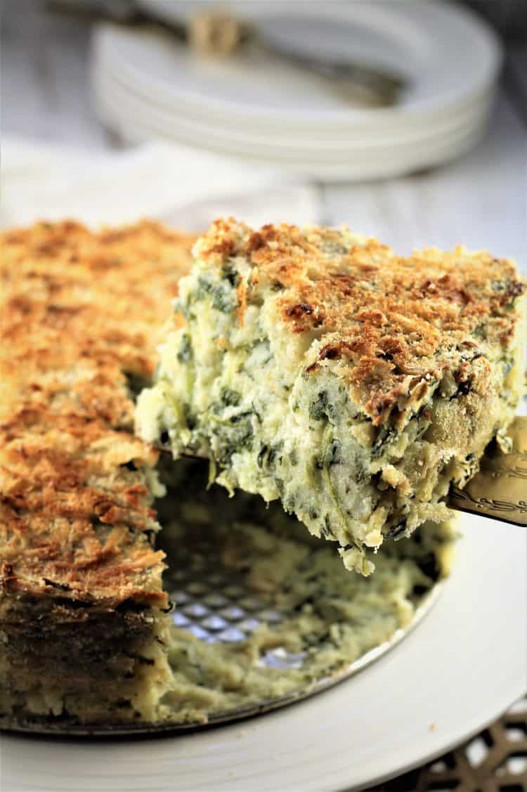 wedge of potato and spinach gateau being cut from whole cake