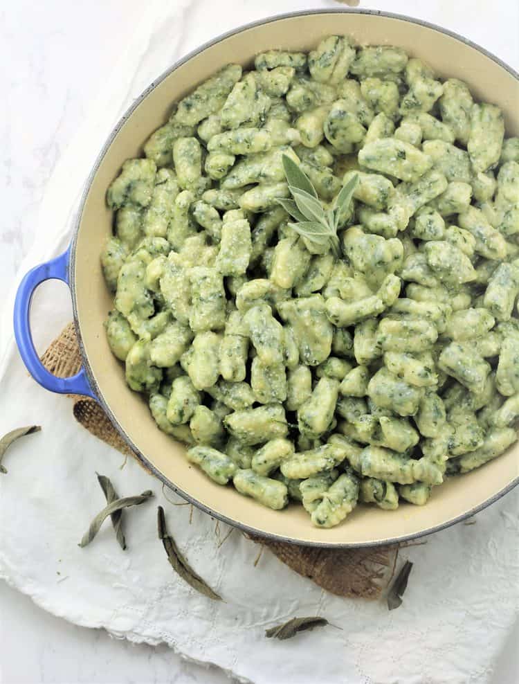 overhead view of blue skillet filled with spinach gnocchi with butter sage sauce