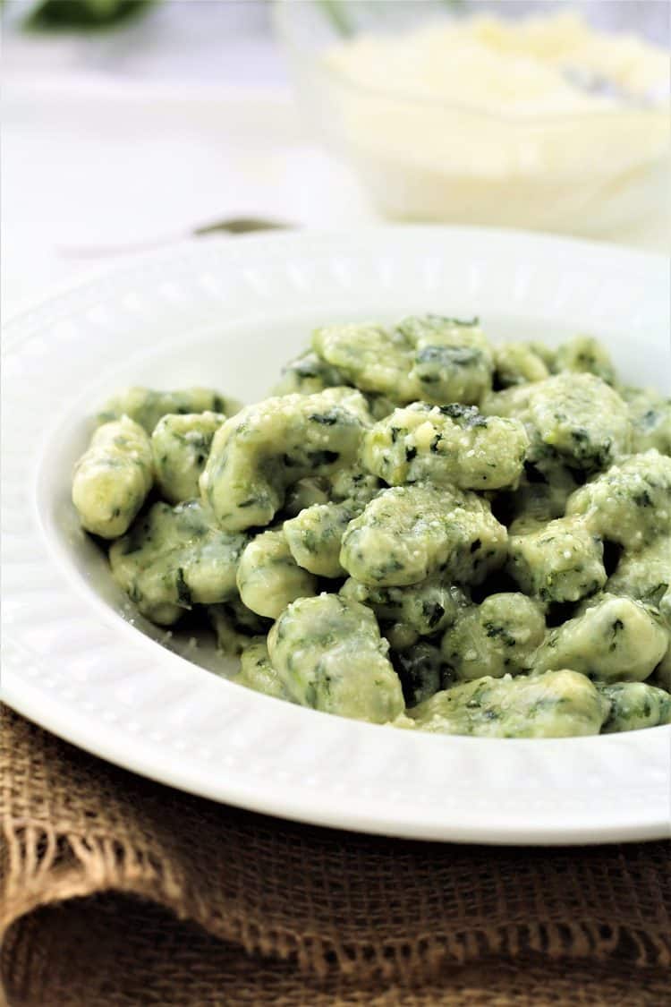 white plate with spinach gnocchi with butter sage sauce