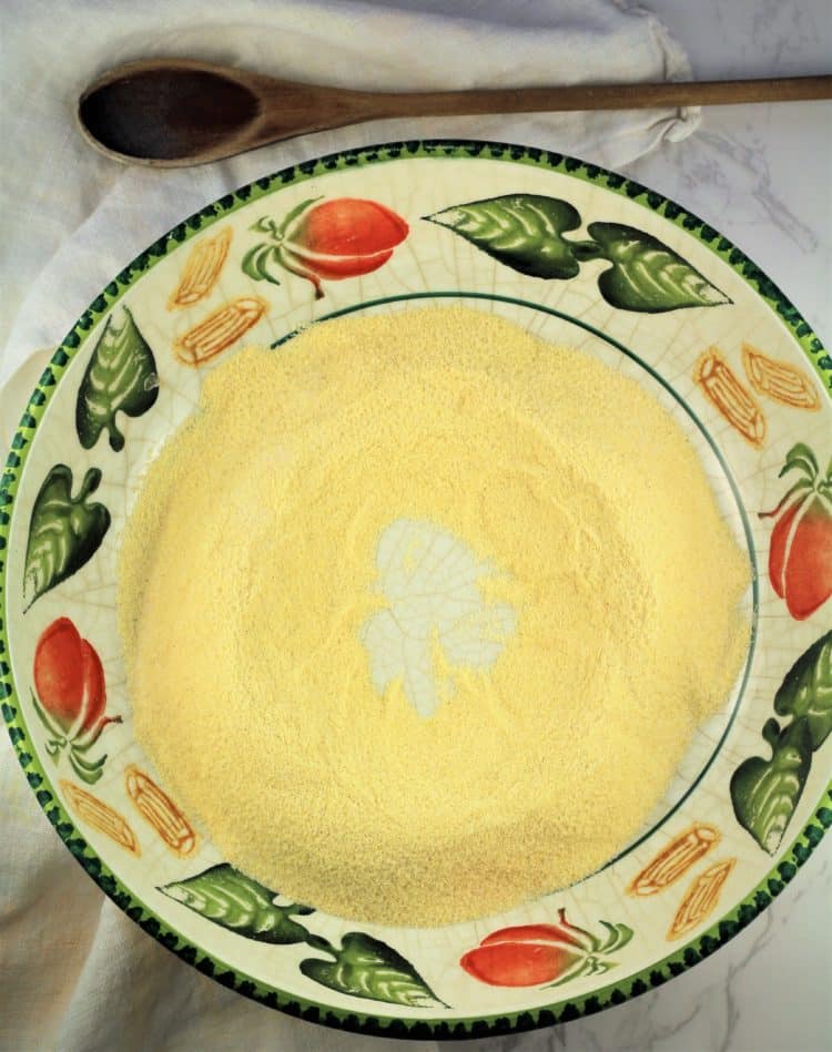colorful large bowl with mound of semolina flour and wooden spoon on side