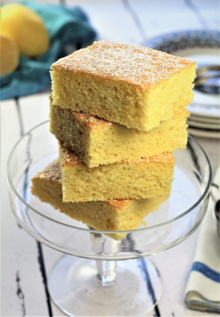 4 squares of vanilla-lemon snack cake piled on glass footed plate