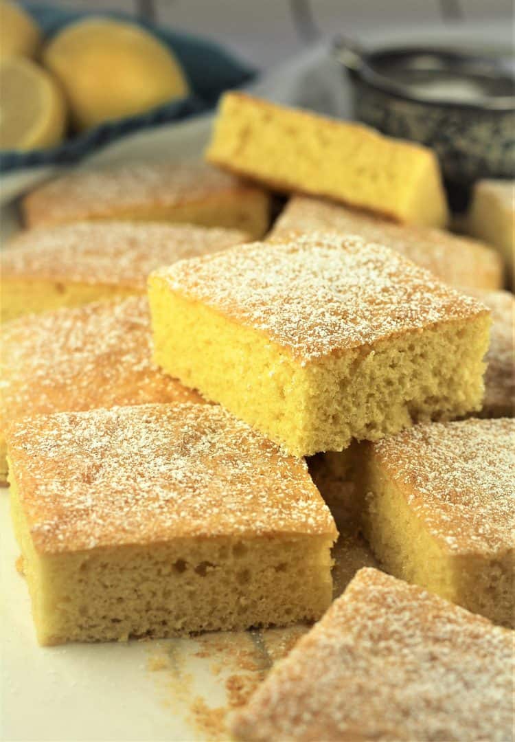 square yellow cake pieces piled on each other with lemons in background