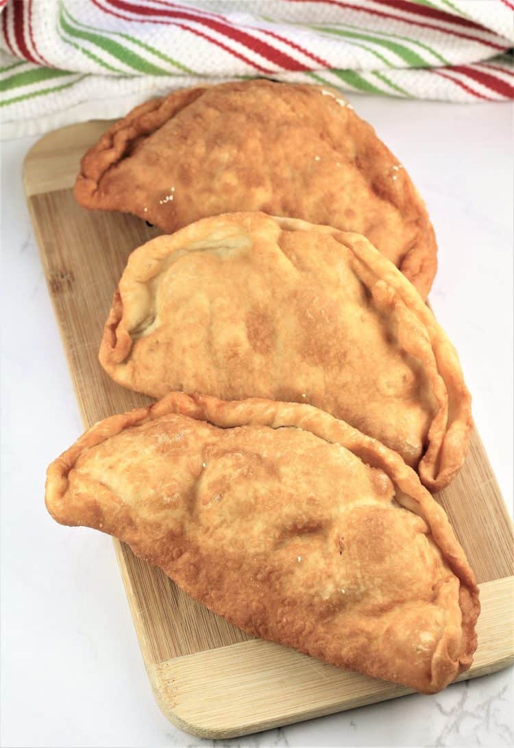 wood board covered with 3 pitoni Messinesi (Sicilian Fried Calzone) just out of the fryer