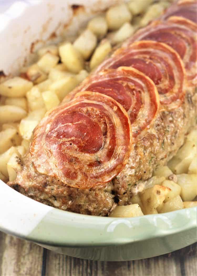 polpettone topped with pancetta slices in roasting pan surrounded by roast potatoes