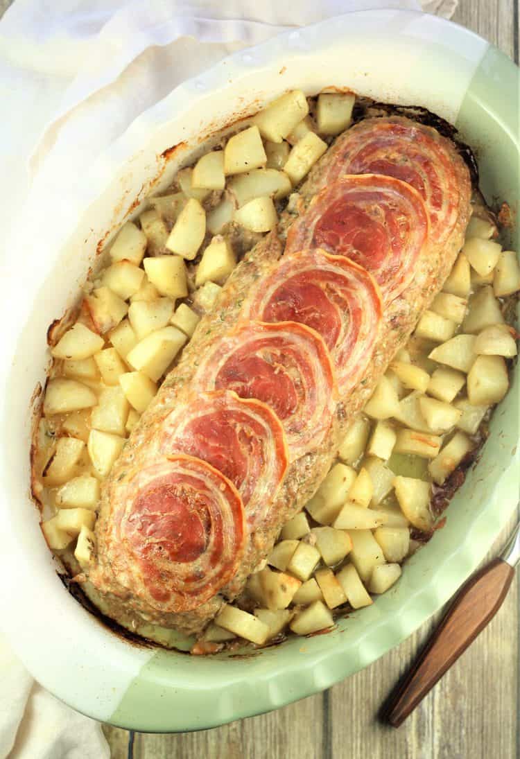 baked polpettone with hard boiled eggs with roast potatoes in casserole dish