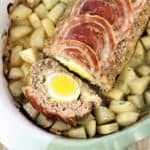 polpettone with hard boiled eggs surrounded by roast potatoes in casserole dish