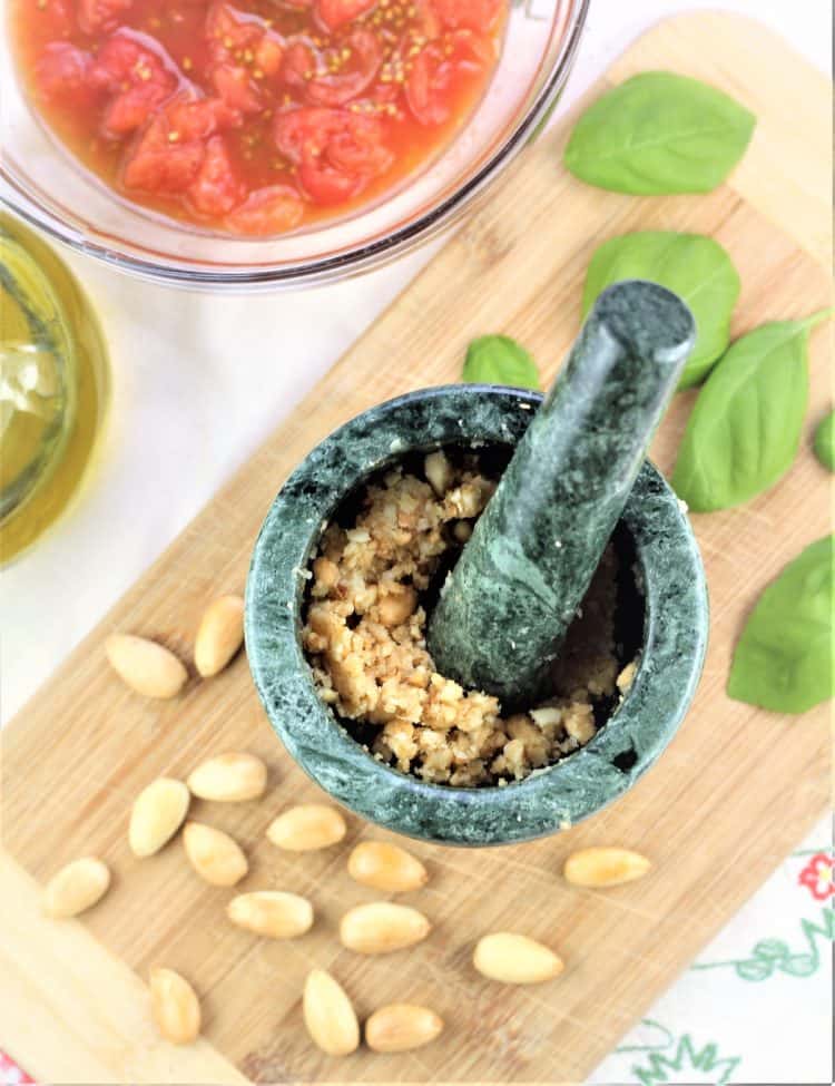 mortar and pestle with ground garlic cloves and blanched almonds 