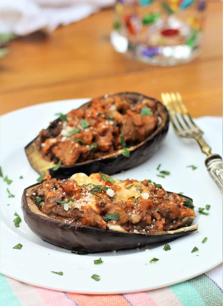 Stuffed Baby Eggplant on white plate with fork on side and glass in background