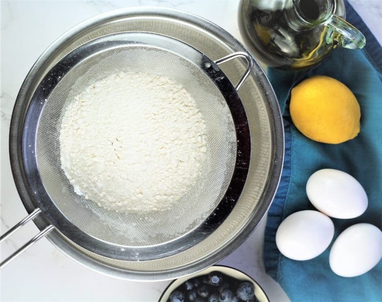 flour sifted into bowl with eggs, lemon and olive oil flask on side