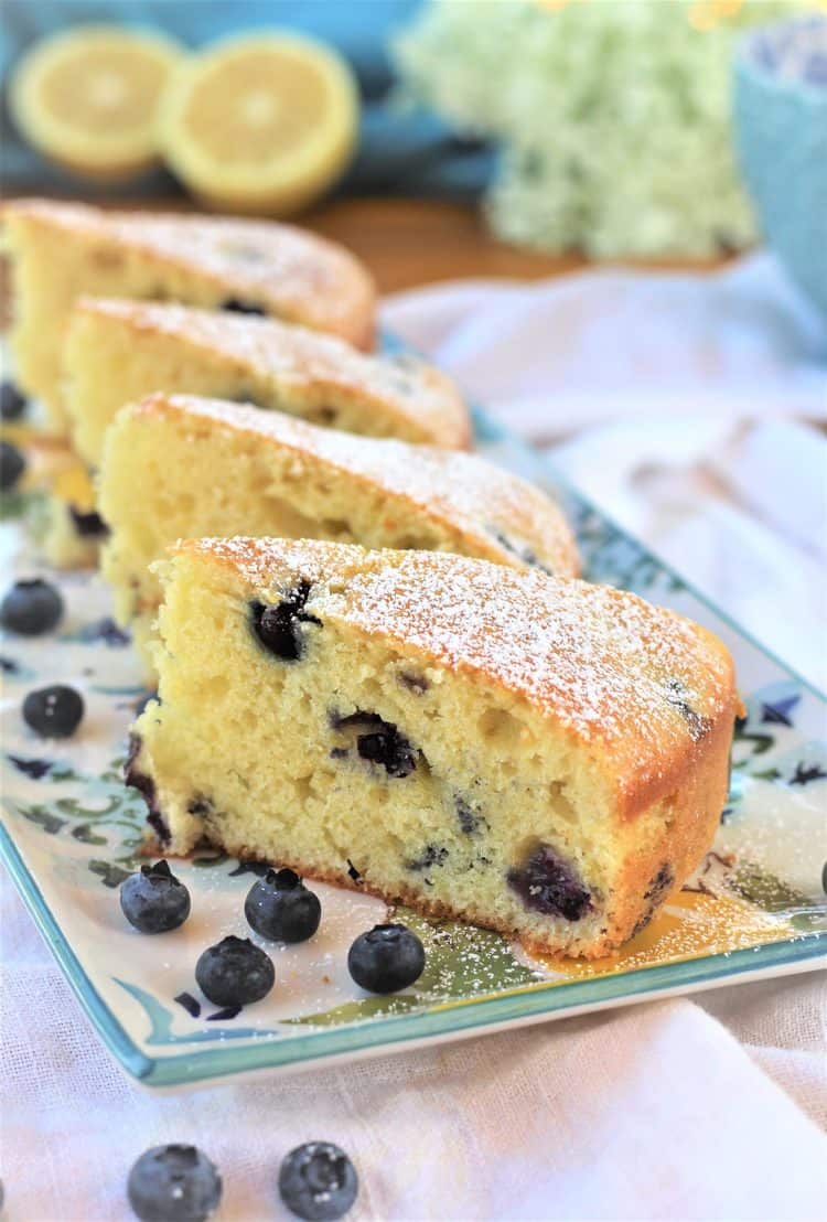 3 slices of blueberry olive oil cake on rectangular plate with lemons in background