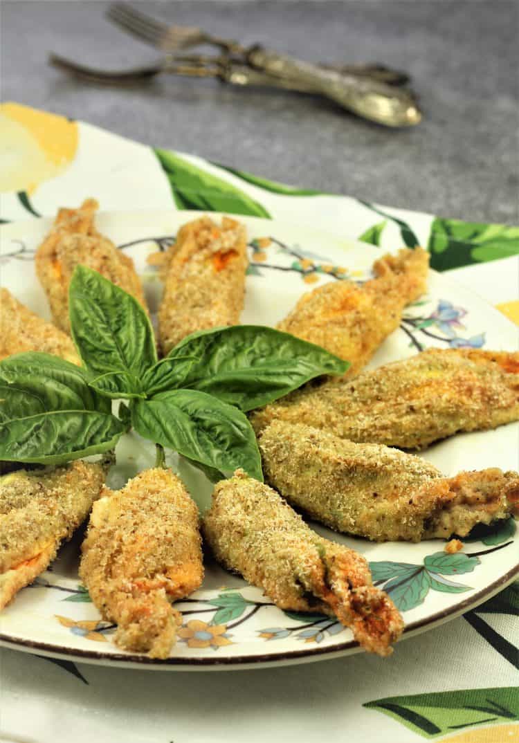 Baked Stuffed Zucchini Blossoms on flowery plate with basil leaves in center