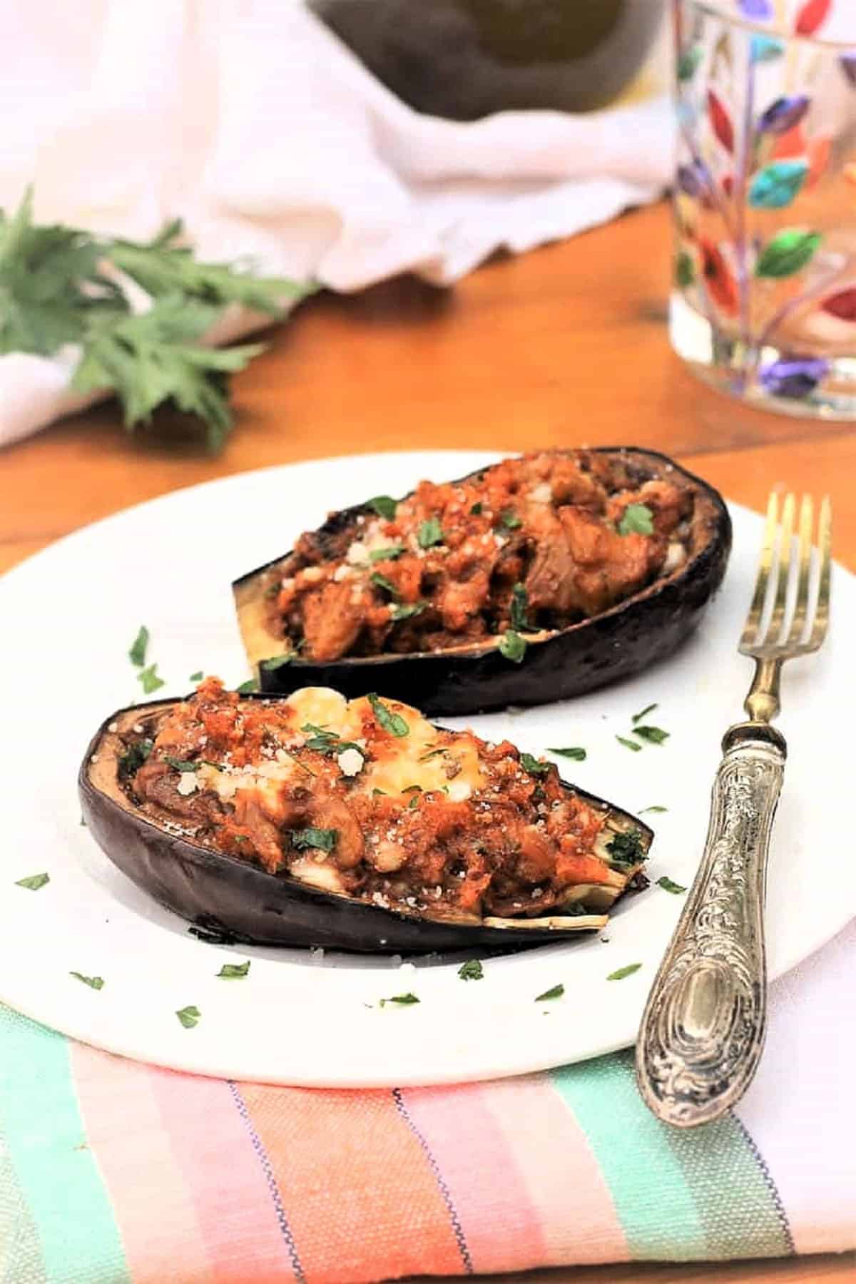 Stuffed Baby Eggplant Stuffed baby eggplant halves with breadcrumbs and cheese on plate with fork.