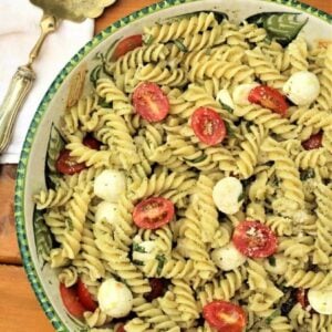 Italain caprese style pasta salad with basil pesto in serving bowl.