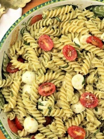 Italain caprese style pasta salad with basil pesto in serving bowl.