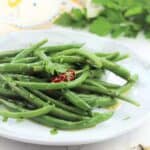 Italian green bean salad topped with oregano on plate with fork on side.