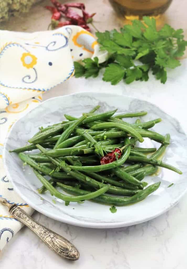 Italian green bean salad on white plate with fork.