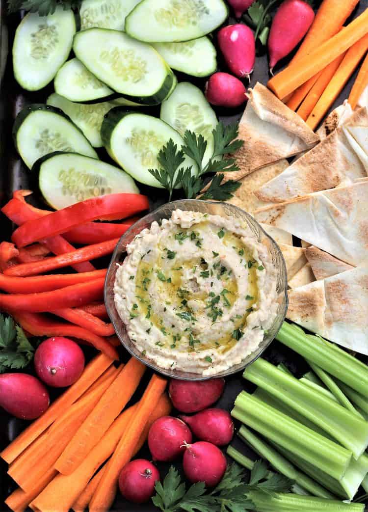 white bean dip in bowl surrounded by crudités and pita crisps