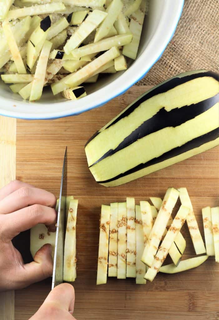 slicing eggplant into strips on wood board