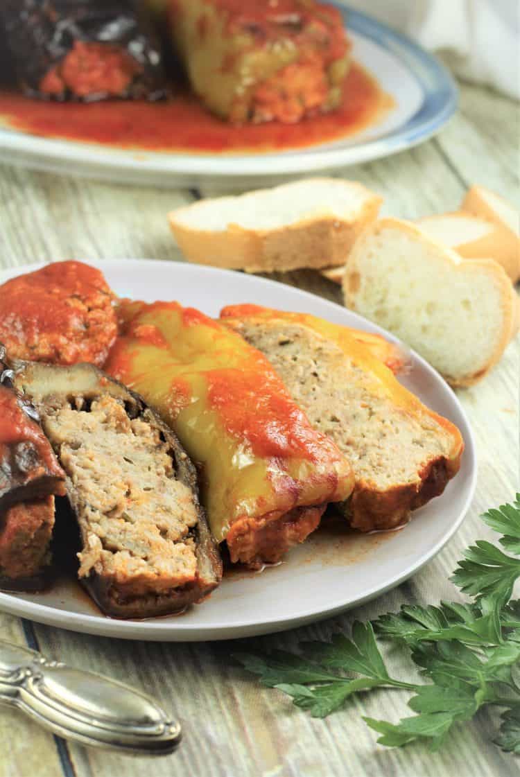 stuffed eggplant and pepper halves on plate with bread slices in background