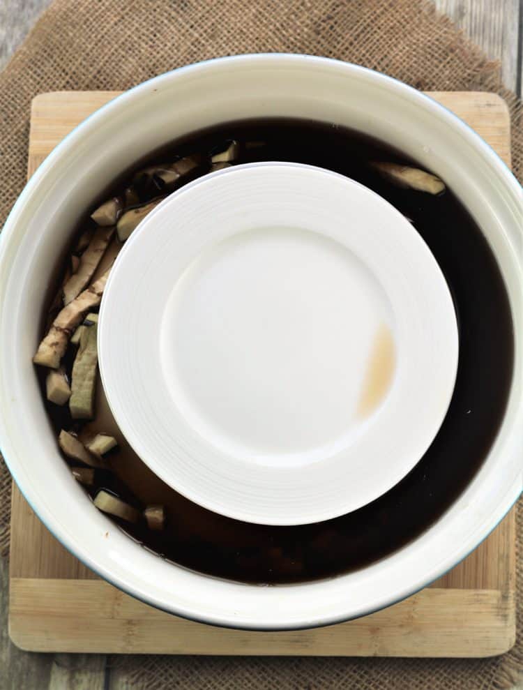 large bowl with eggplant soaking surrounded by dark water